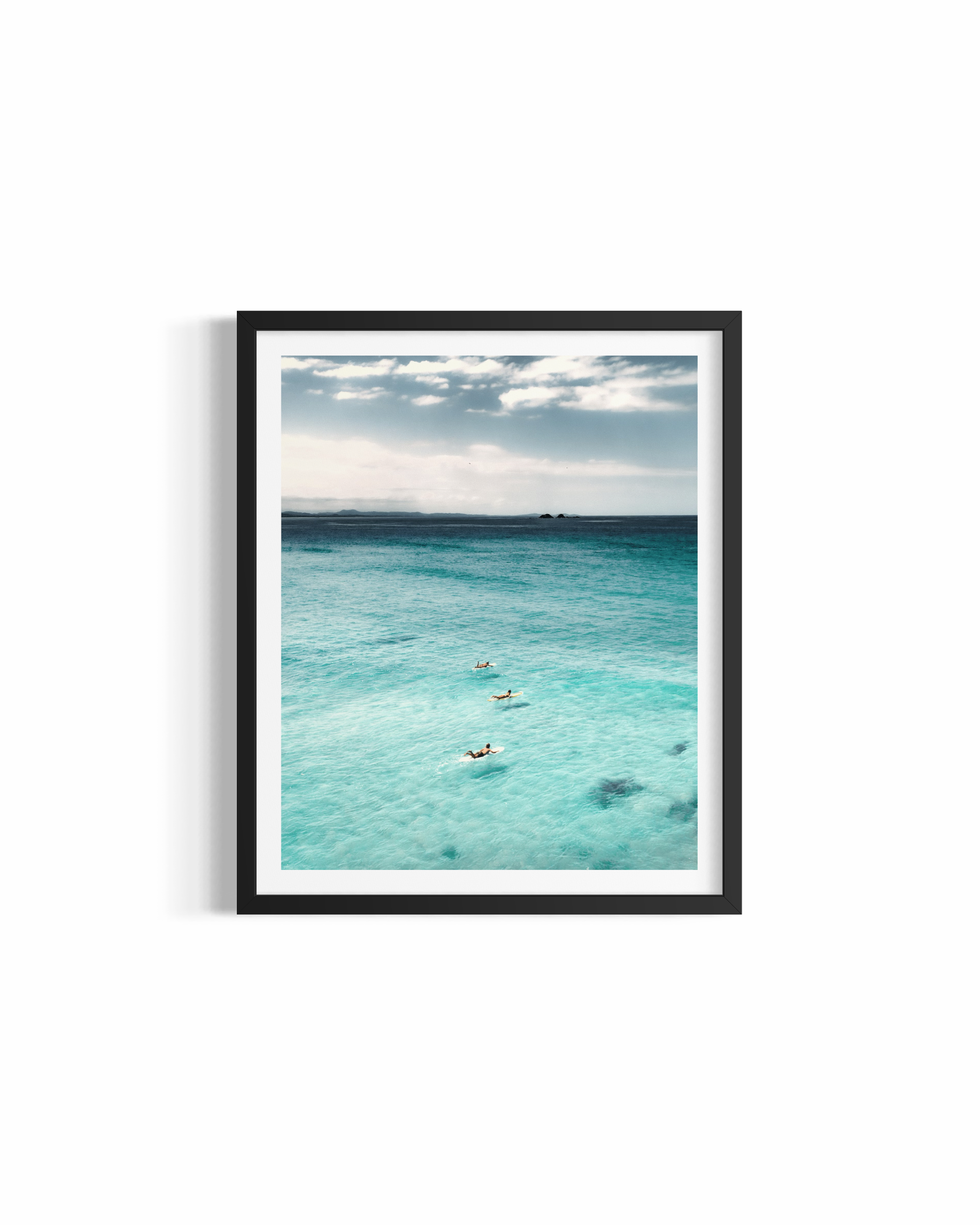 Three surfers paddling through turquoise water at Wategos Beach with Julian Rocks on the horizon — Journey print by Saxon Kent