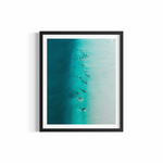 A dozen dolphins surfing through a turquoise wave at Wategos Beach — Party Wave fine art print by Saxon Kent