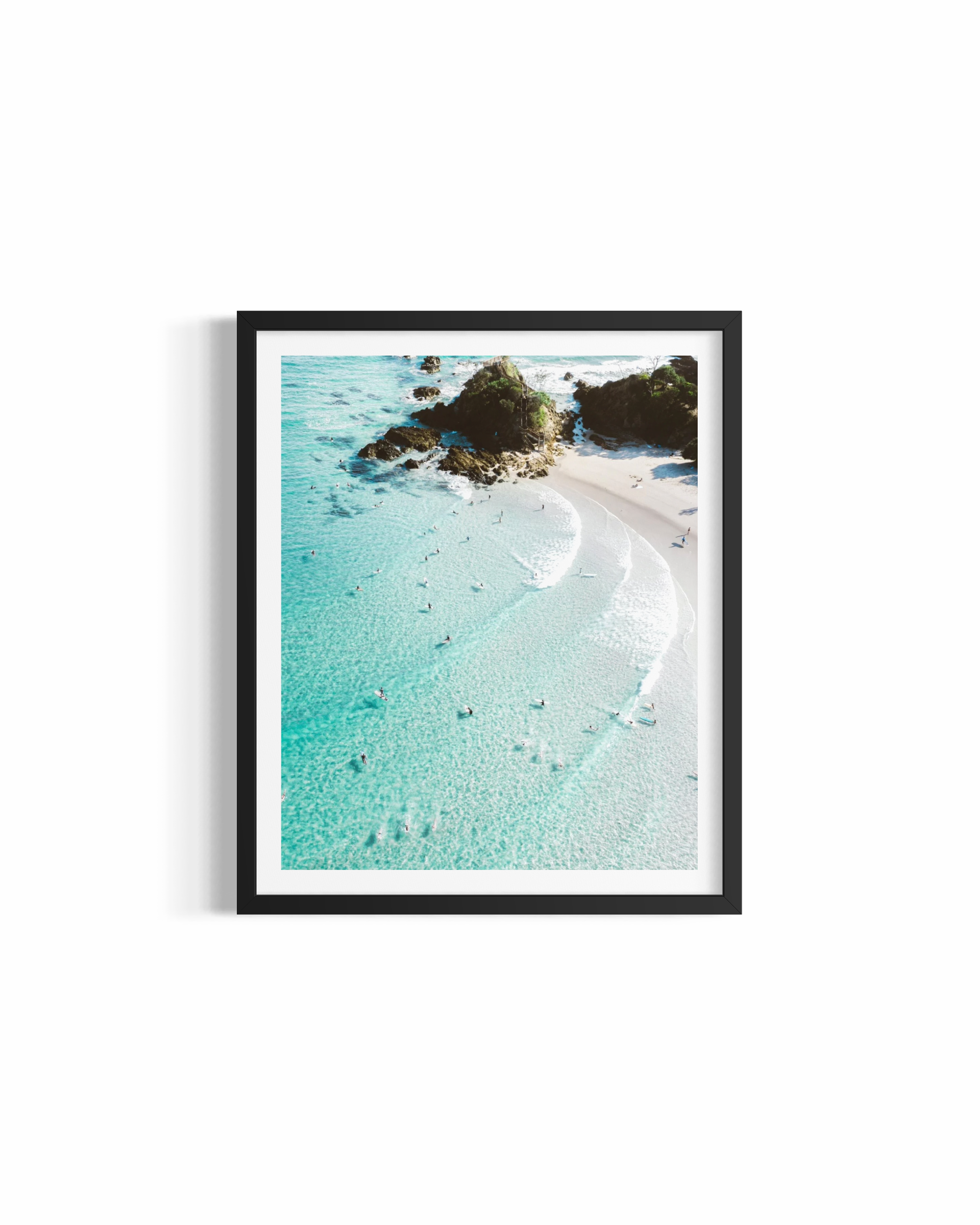 Aerial view looking down on The Pass Byron Bay with turquoise water, surfers and rocky headland — Down the Line by Saxon Kent